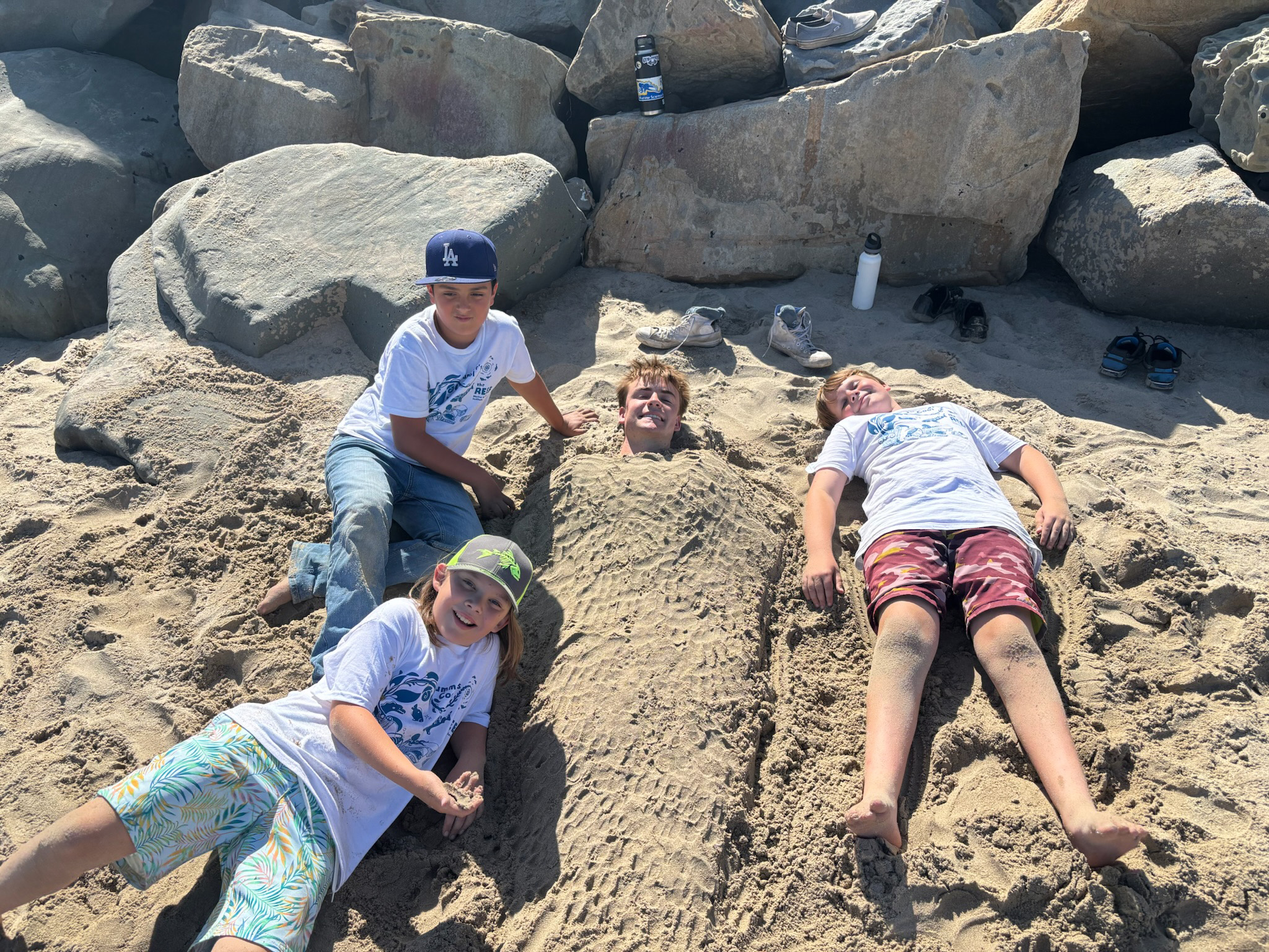 REEF campers posing on sand next to buried docent